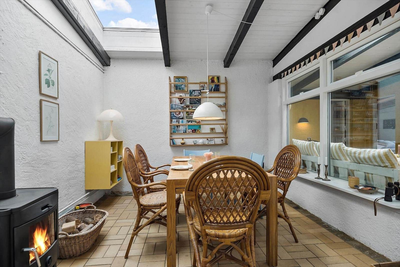 Dining area with table, chairs, and wood stove under roof