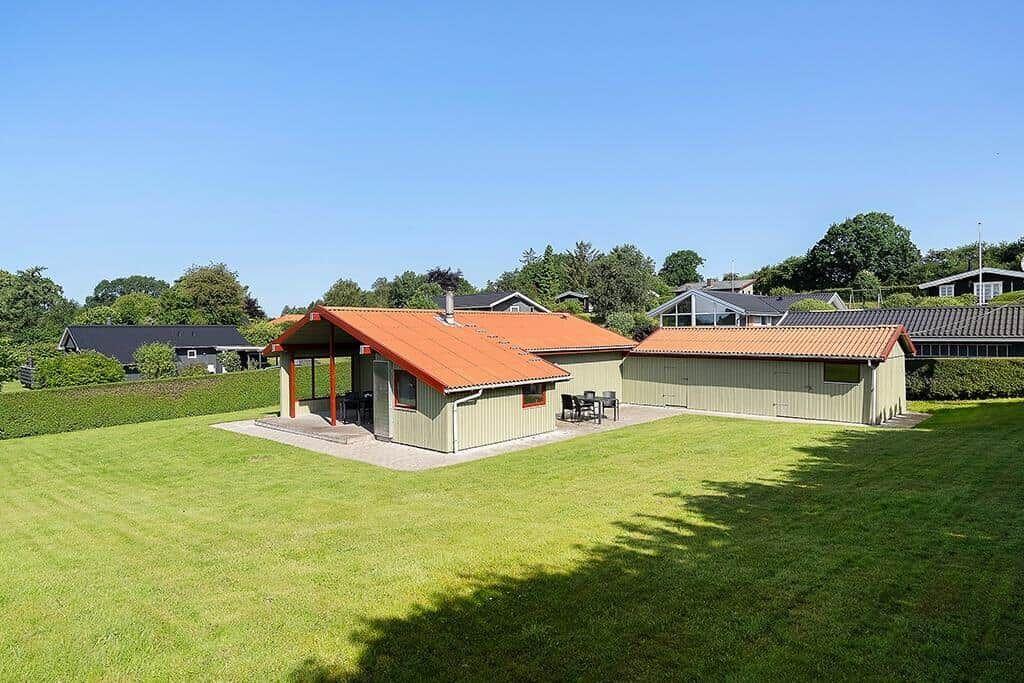 Haus mit orangefarbenem Dach und großem Garten. Außenterrasse mit Tisch und Stühlen.
