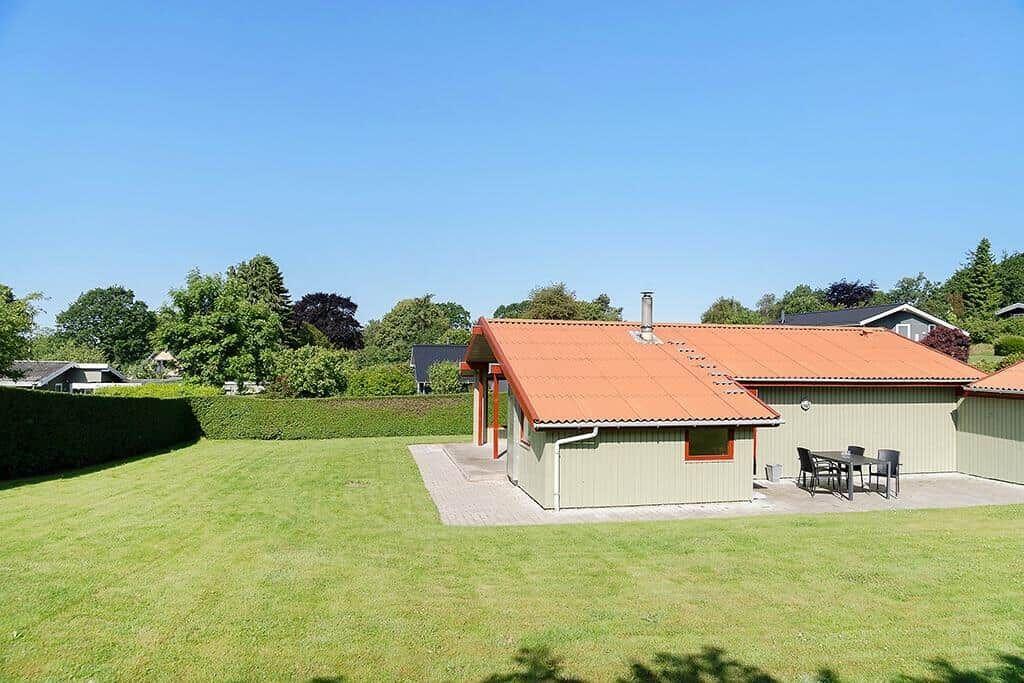 Haus mit orangefarbenem Dach und großem Garten. Außentisch und -stühle sind vorhanden.
