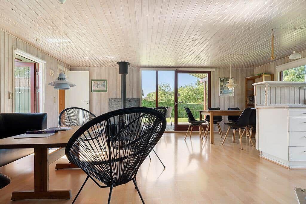 Wohn- und Essbereich mit Holzboden, schwarzen Stühlen und Blick auf den Garten.
