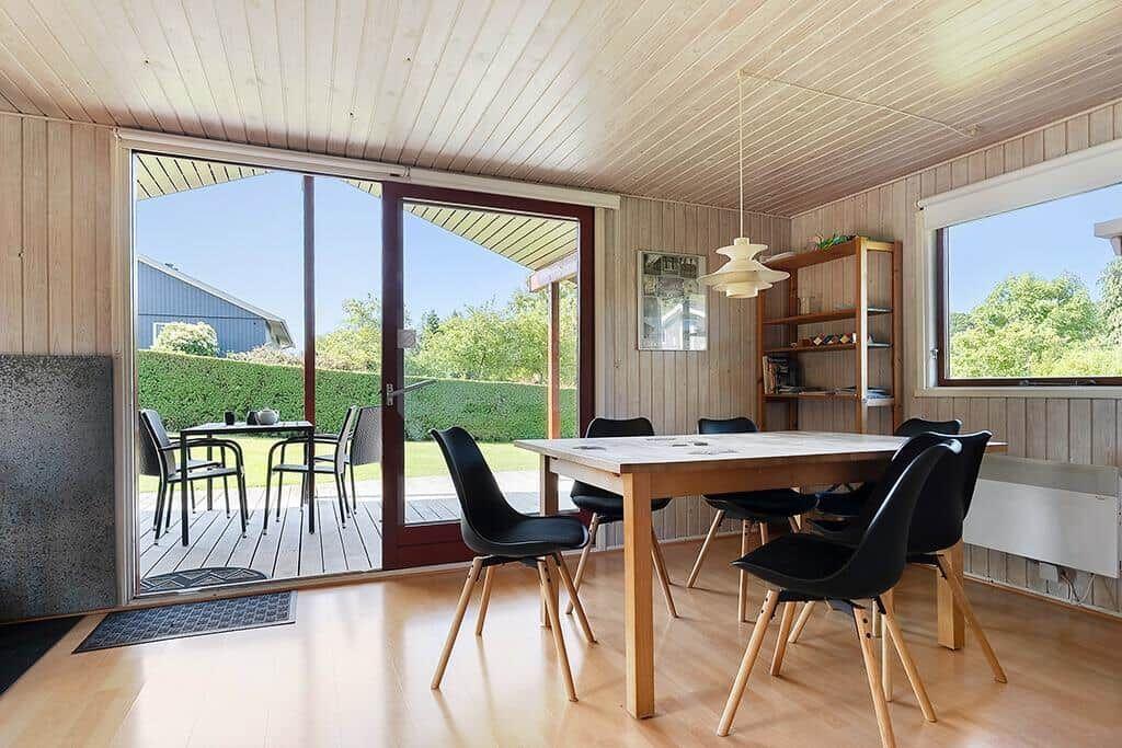 Esszimmer mit Holztisch, schwarzen Stühlen und Blick auf die Terrasse.