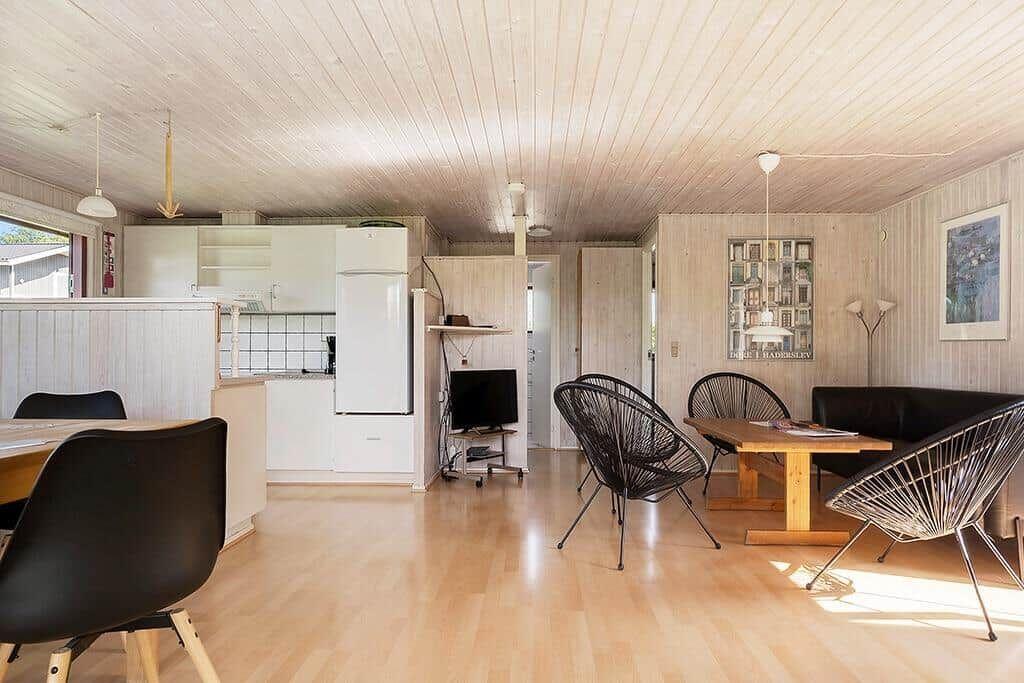 Wohnbereich mit Essbereich, Küche und Wohnzimmer mit Holzboden und schwarzen Stühlen.