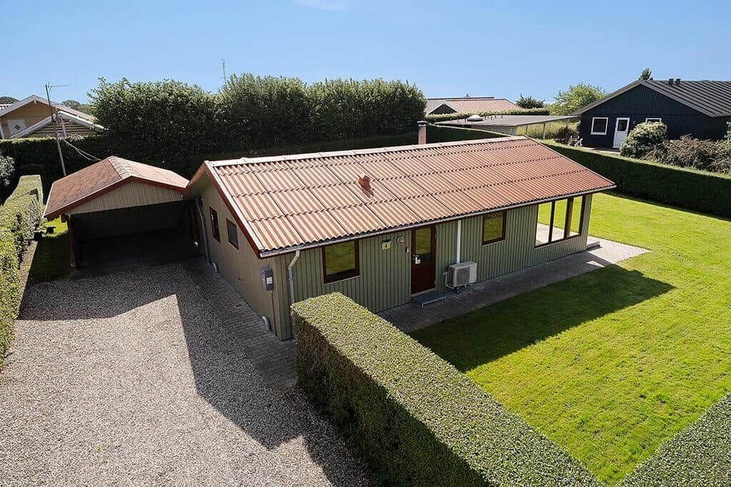 Ein Haus mit Garage, Rasen und Hecken. Dach und Wände sind sichtbar.