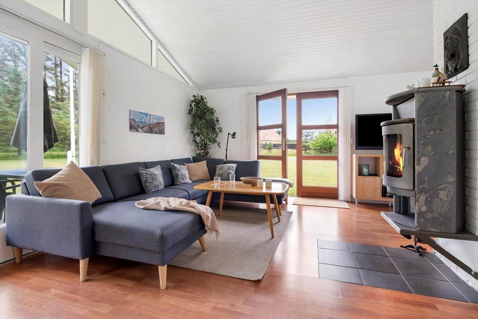 Wohnzimmer mit Sofa, Kamin und großen Fenstern zur Aussicht.