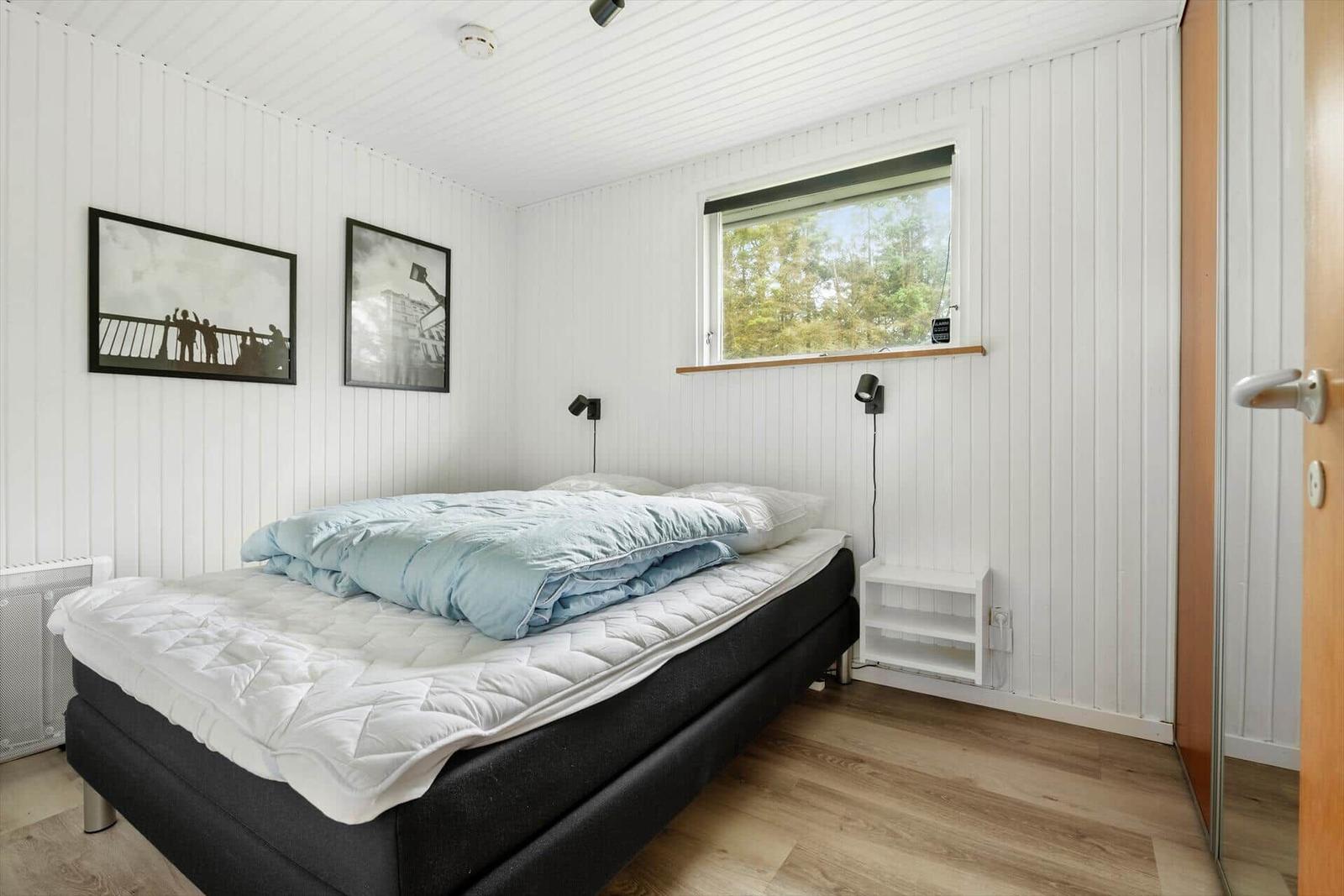 Schlafzimmer mit Bett, Fenster und Wandbildern.