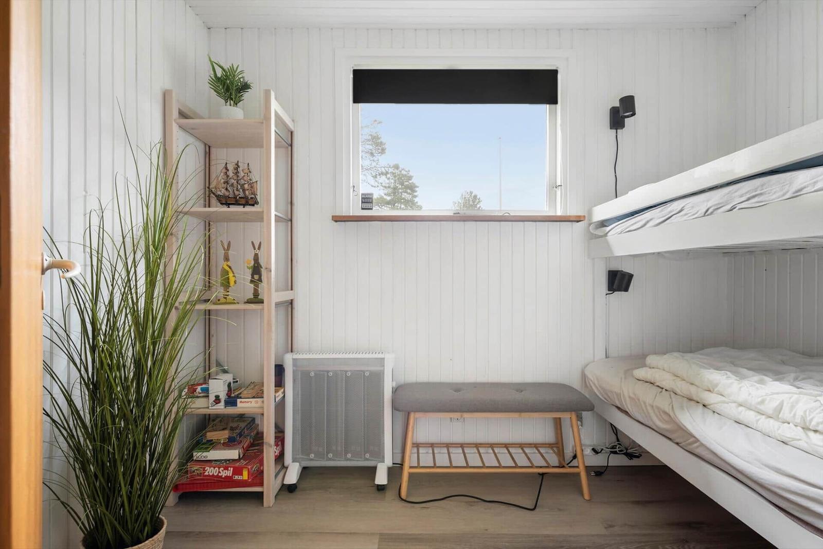 Zimmer mit Doppelstockbett, Regal, Pflanze und Fenster mit Blick.