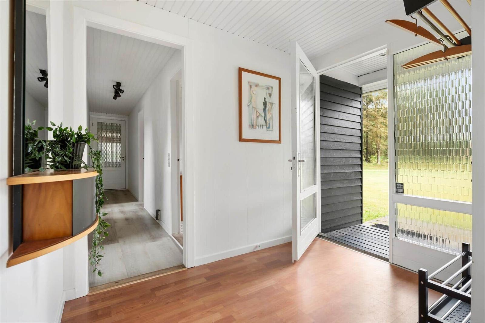 Haus mit Holzboden, weißen Wänden und Glasfront zum Garten.