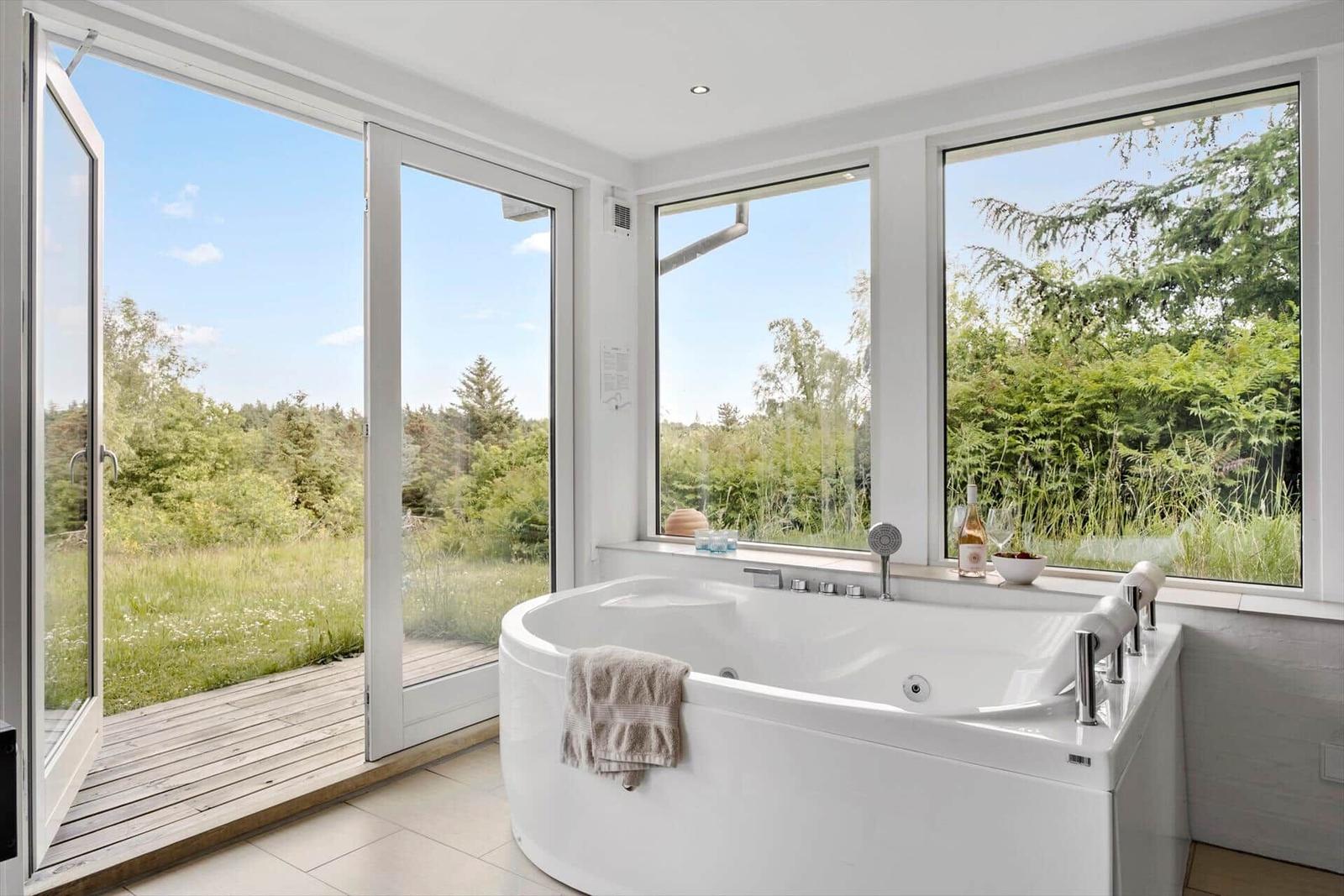 Jacuzzi bath with view of garden and forest.