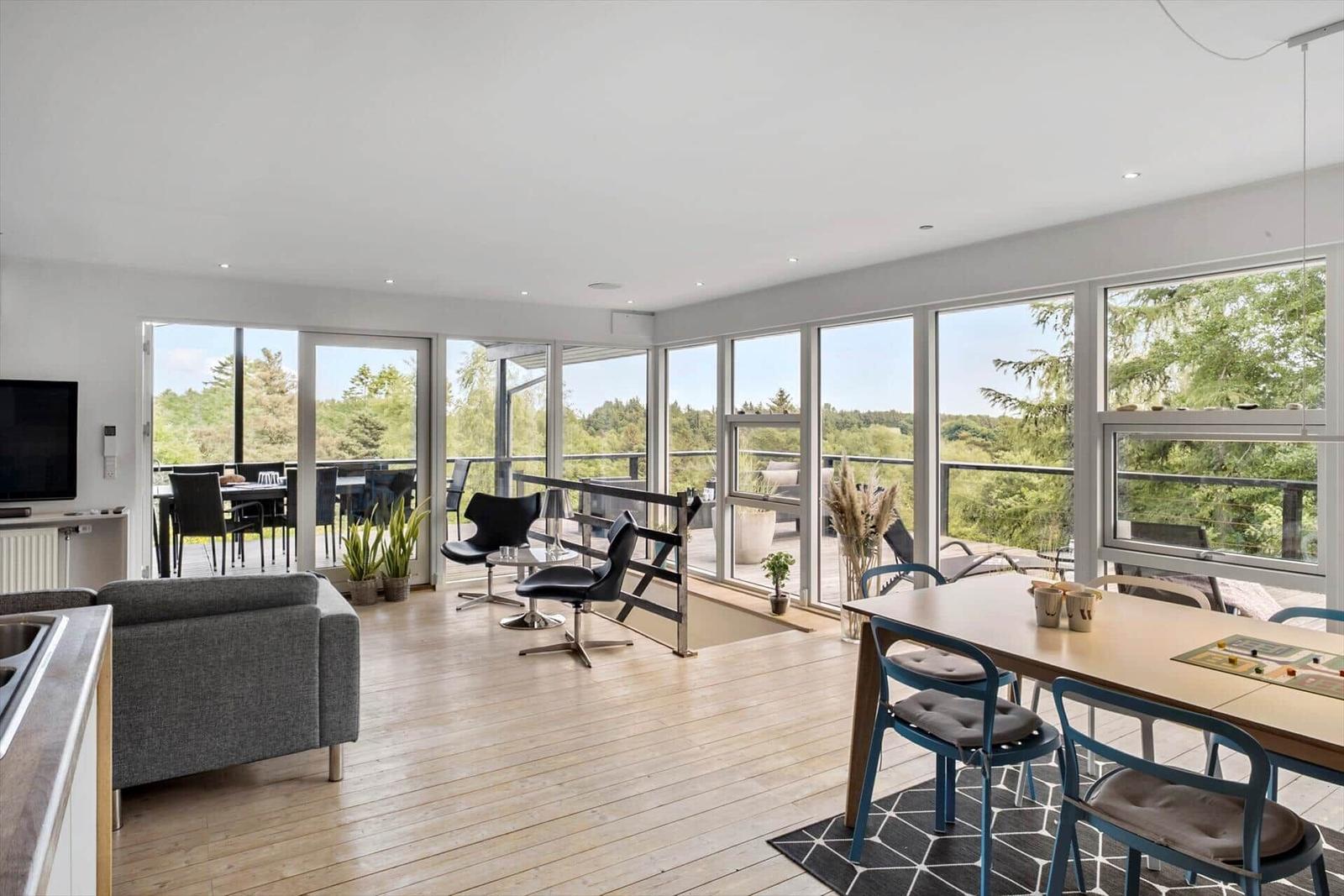Large living and dining area with view of balcony and forest.