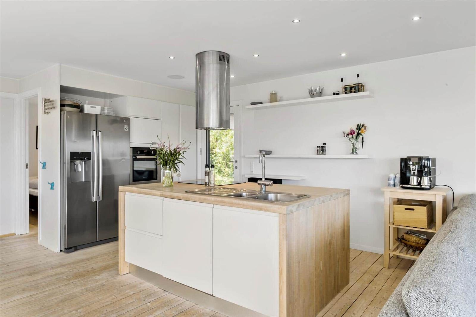 Kitchen with island, stainless steel fridge, and range hood.