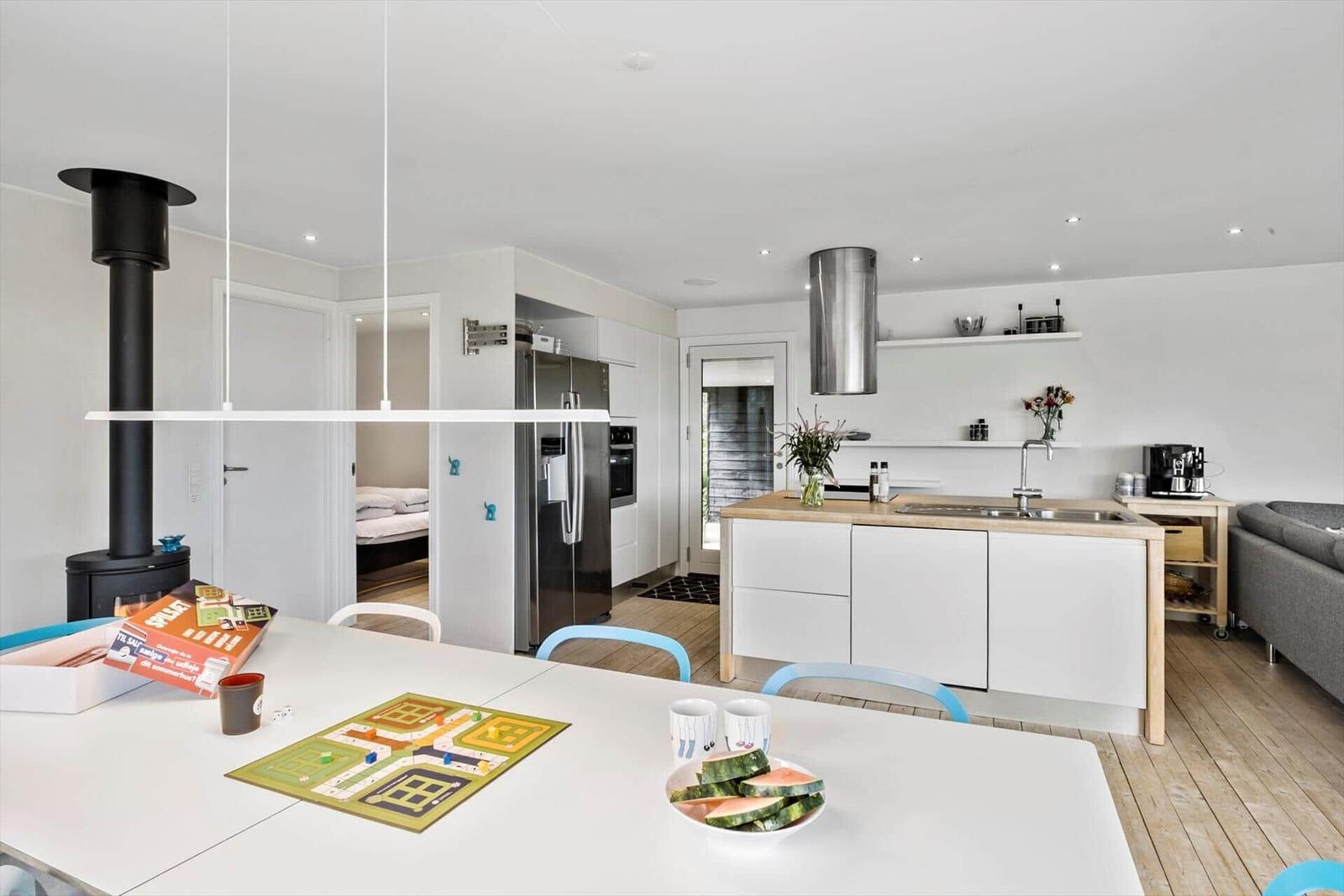 Kitchen with dining area, dining table, game, and watermelon.
