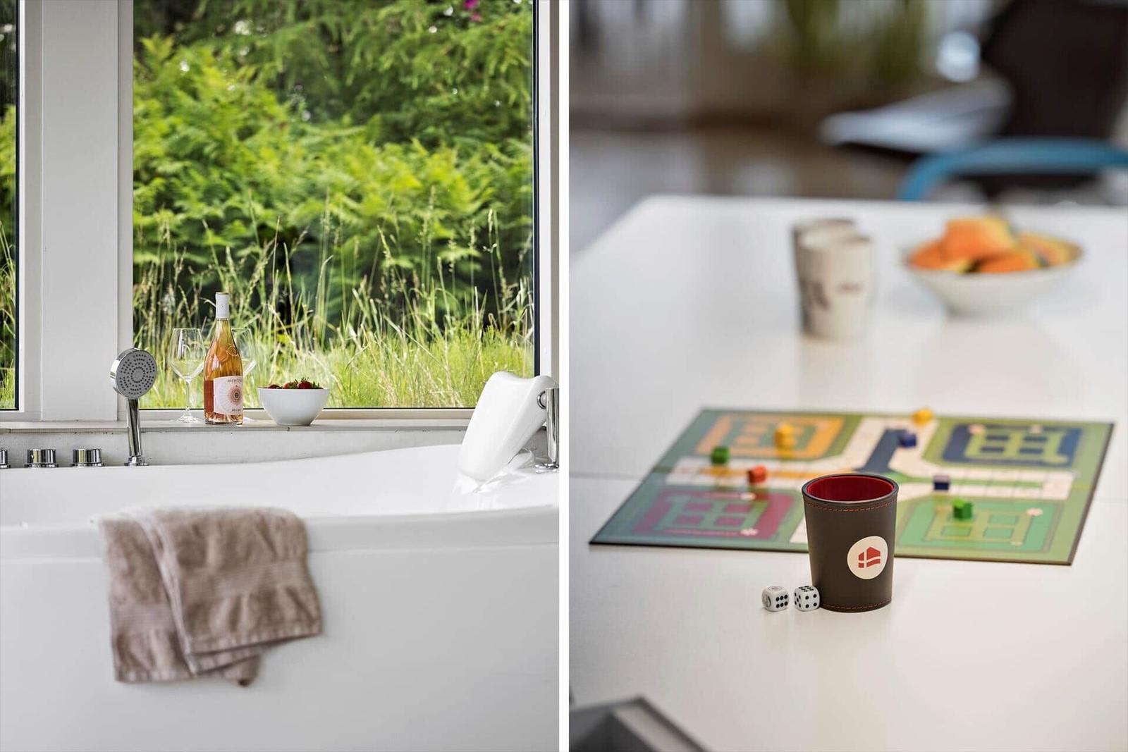 Bathtub with view of green vegetation. Table with game and fruit.