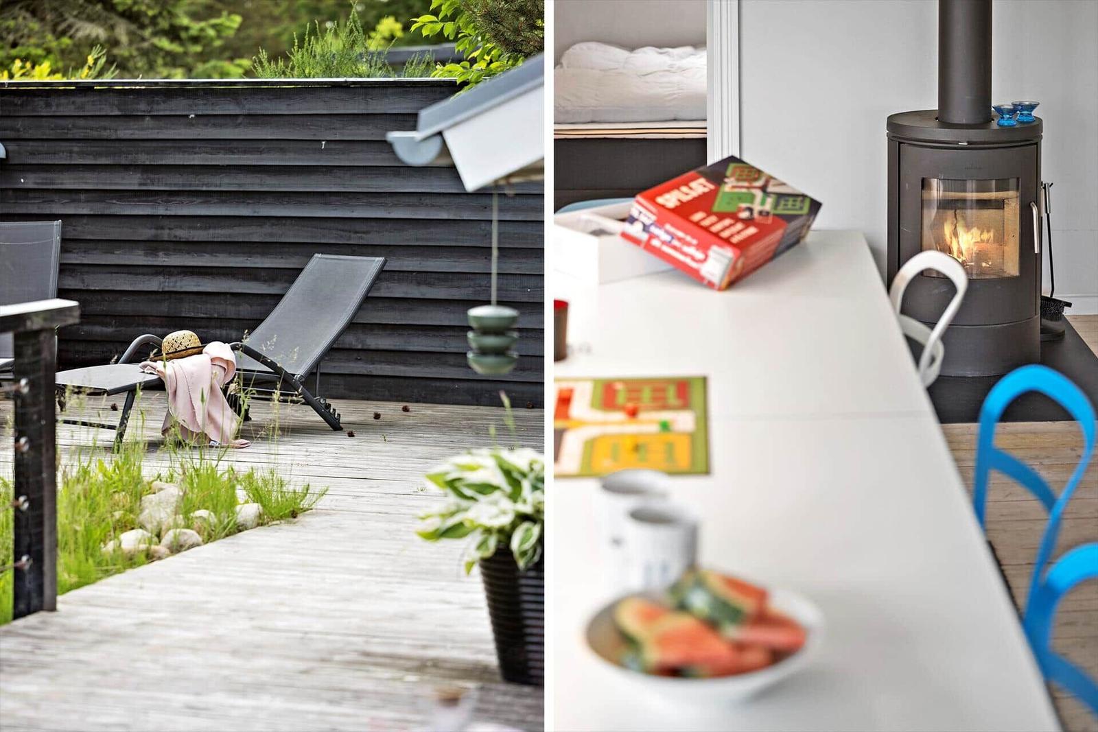 Deck with lounge chair and green view. Inside: table with game and wood stove.