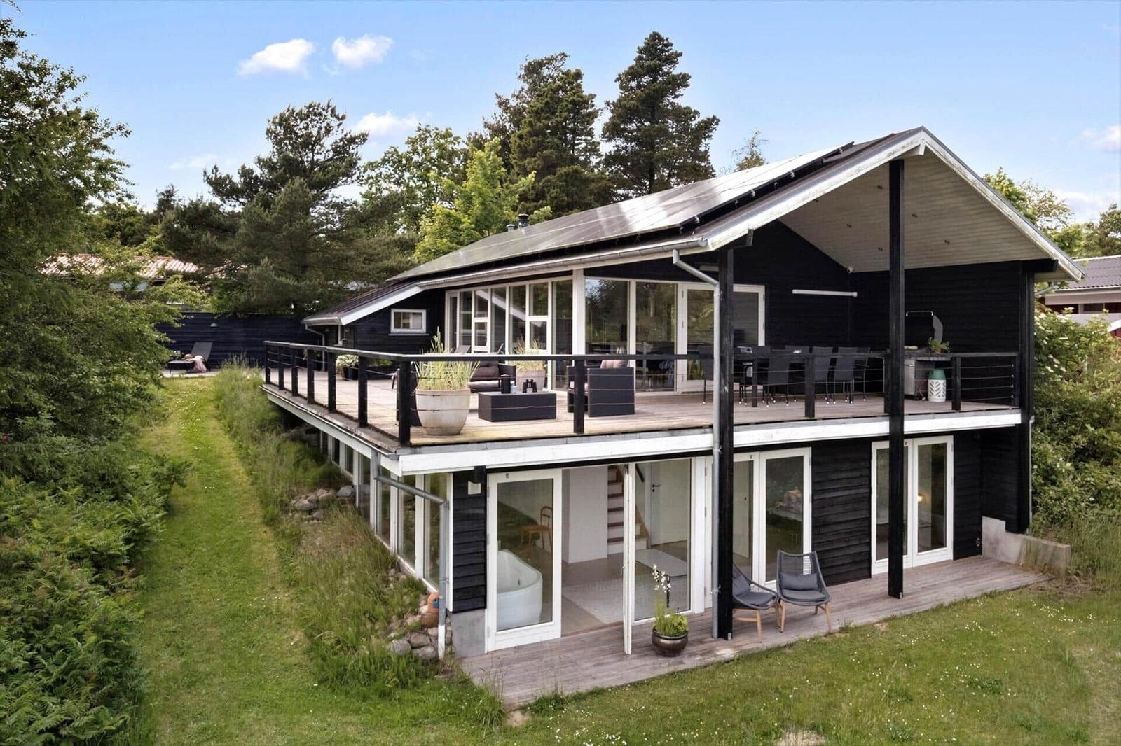 Modern villa with large balcony, glass facades, and outdoor shower.