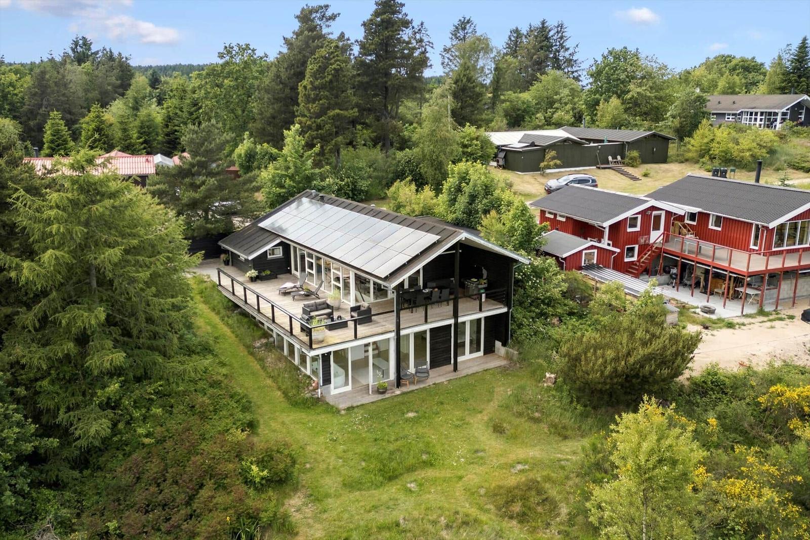 Modern house with terrace and forest view. Adjacent red houses.