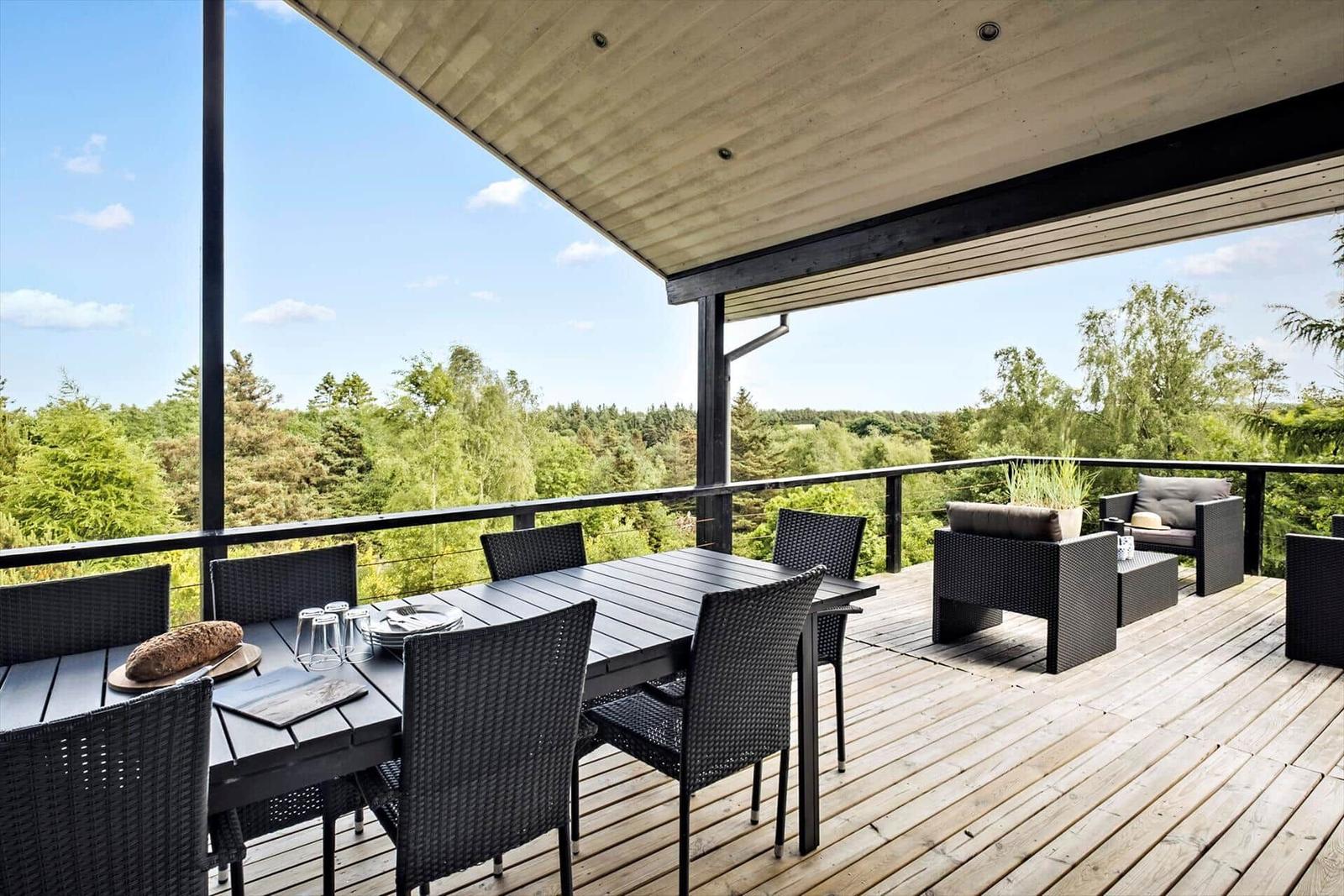 Deck with table, chairs, and view of forest.