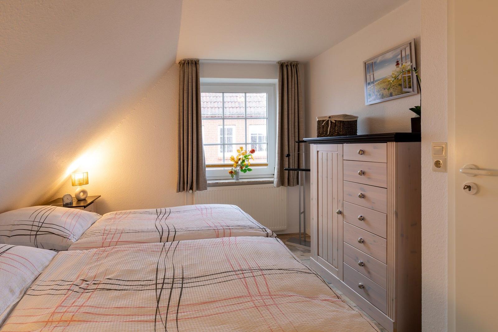 Schlafzimmer mit Doppelbett, Fenster und Kleiderschrank.