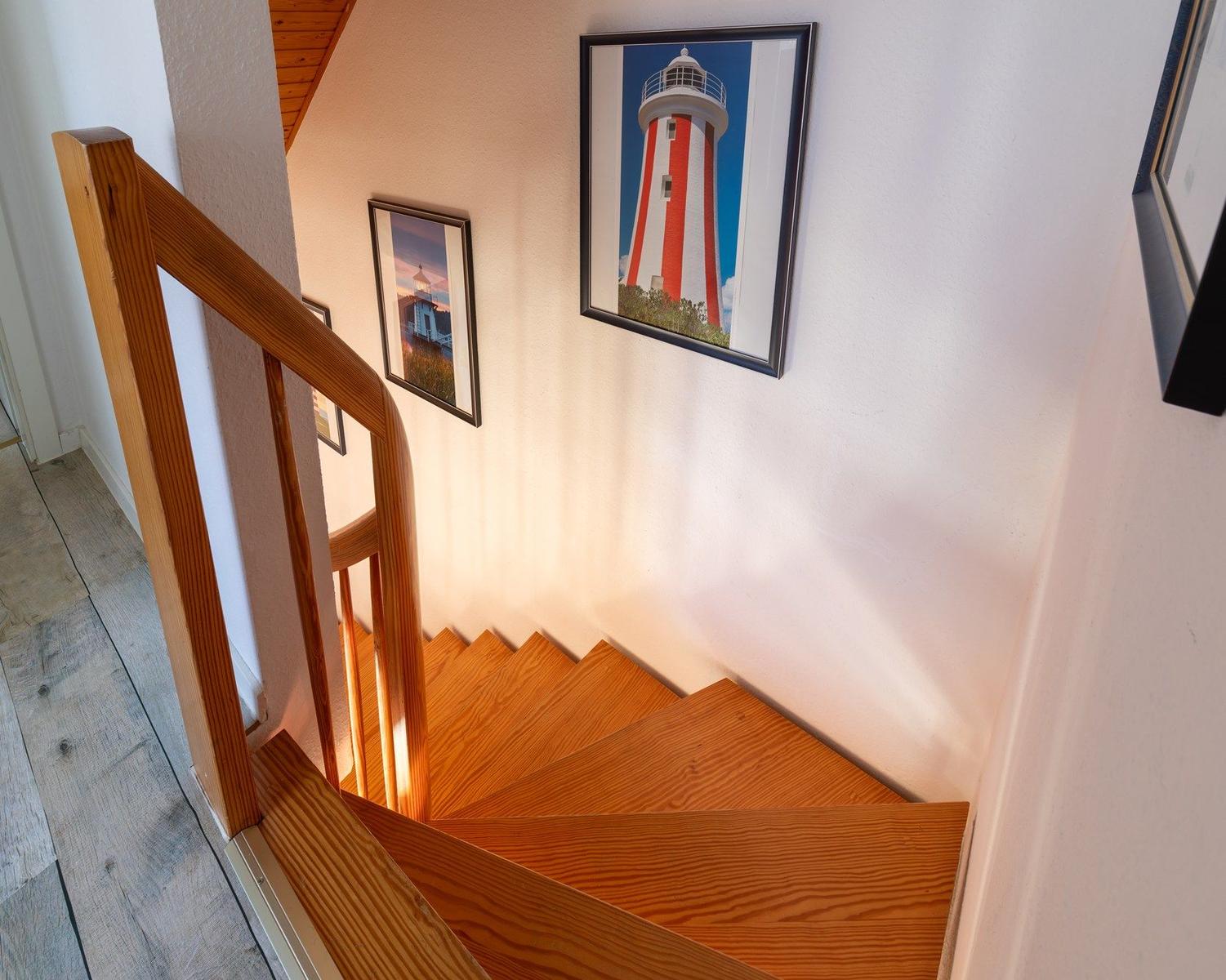 Holzgetreppe mit Geländer und Wandbildern an der Wand.