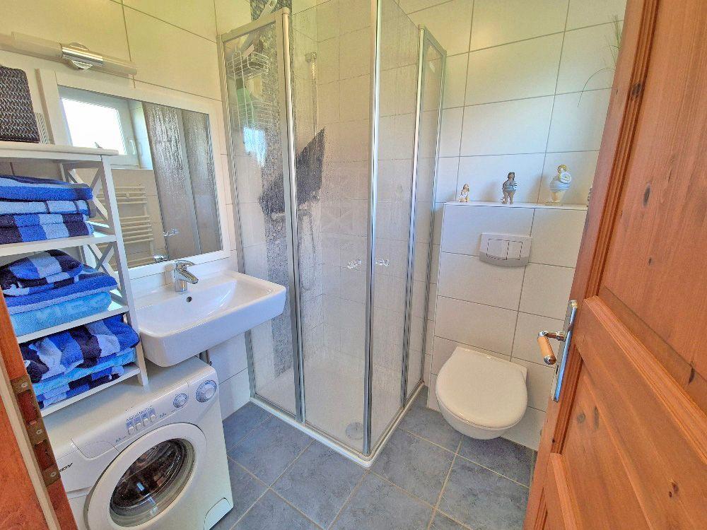 Badezimmer mit Dusche, Waschbecken und Waschmaschine.