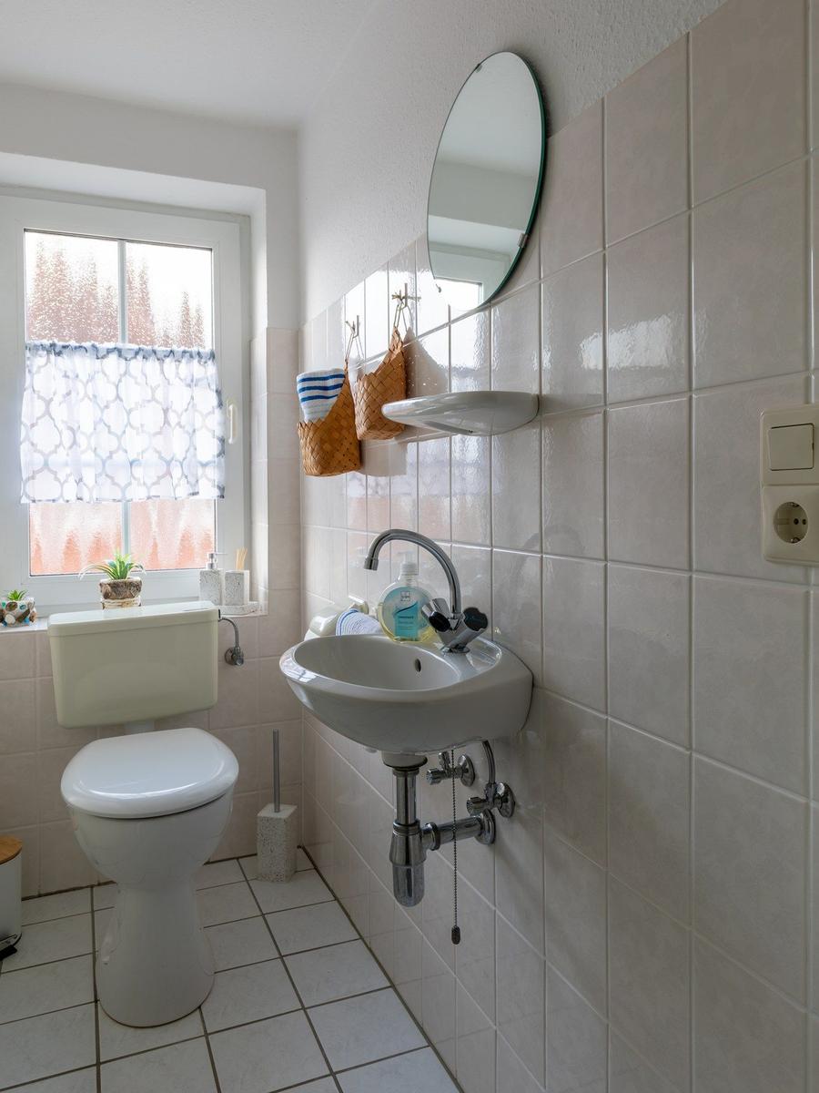 Badezimmer mit Toilette, Waschbecken und Spiegel an der Wand.