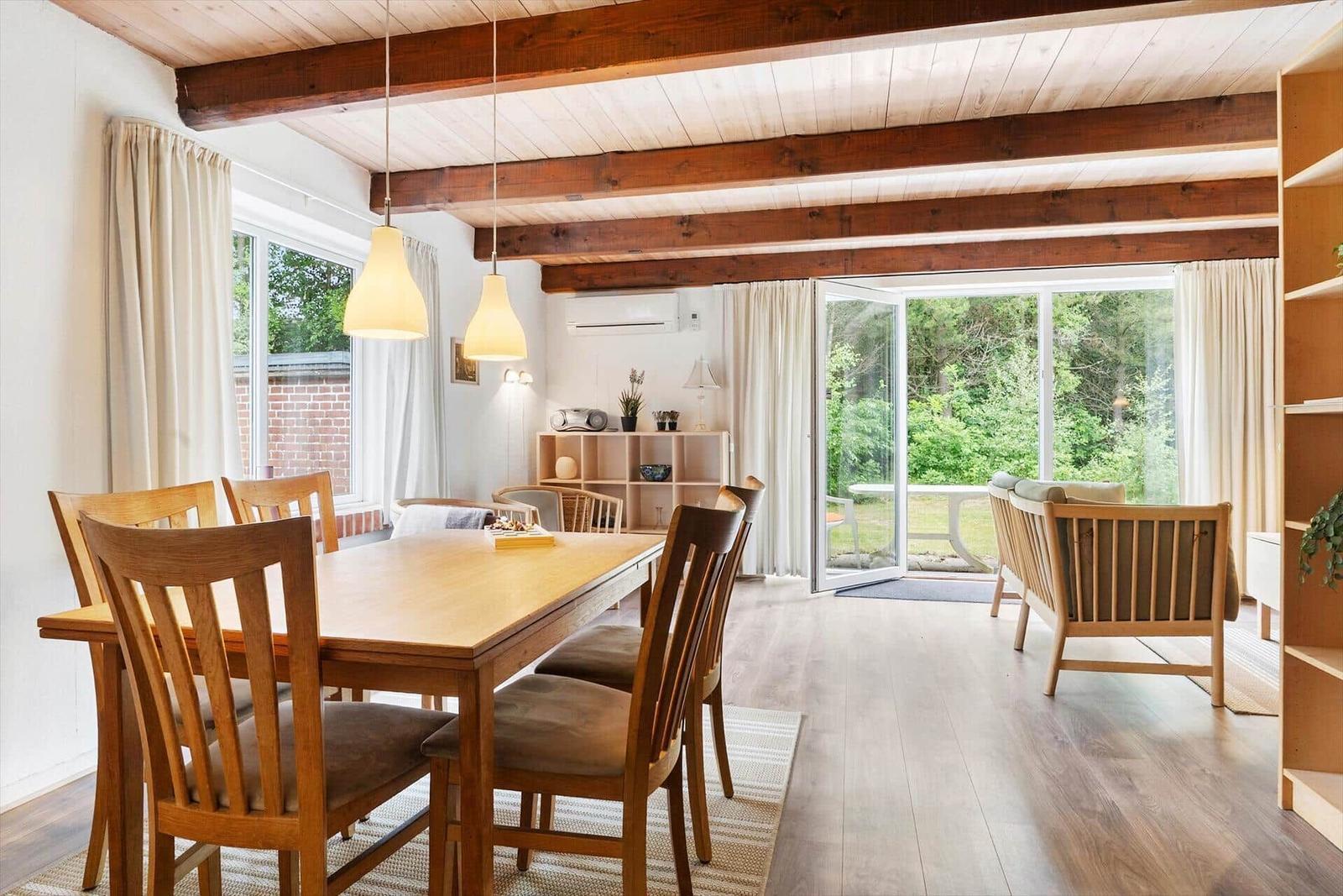 Essbereich mit Holztisch und Stühlen, Sitzgelegenheiten und Blick auf Garten.