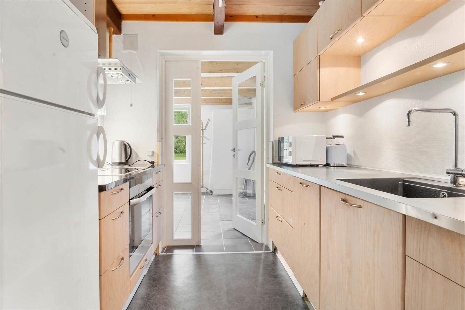 Küche mit Holzschränken, Kühlschrank, Herd und Spüle.