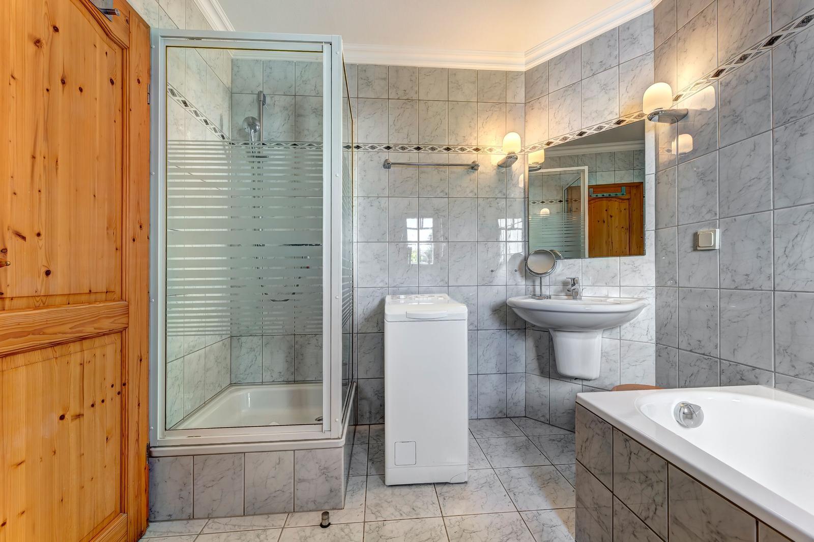 Badezimmer mit Dusche, Waschmaschine, Waschbecken und Badewanne.