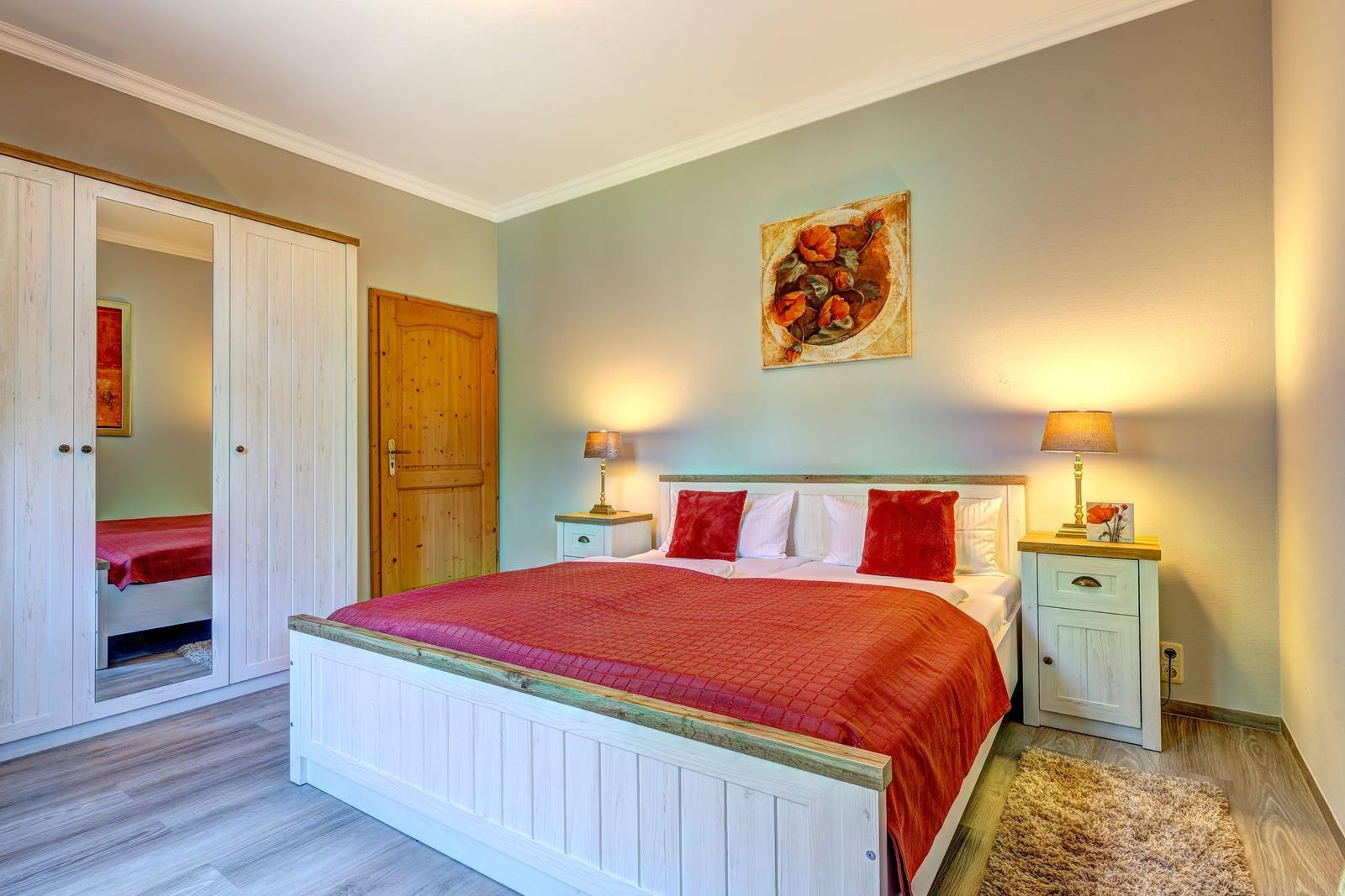 Schlafzimmer mit Bett, Nachttischen und Kleiderschrank.