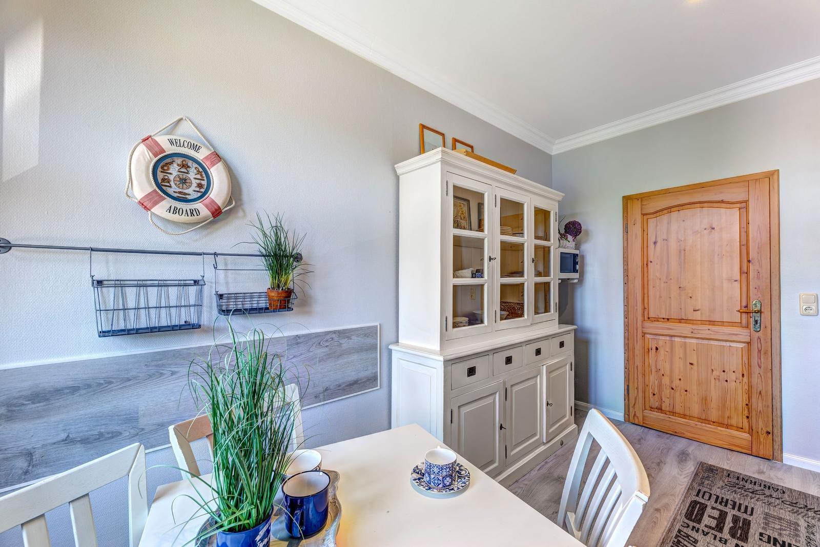 Esszimmer mit Tisch, Stühlen, weißen Schränken und Holztür.