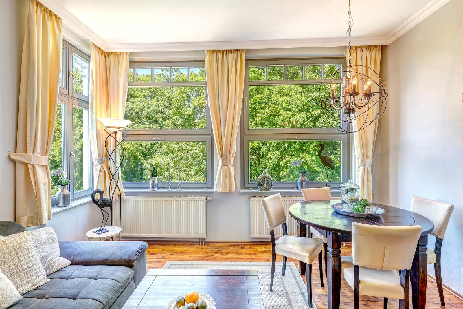 Esszimmer mit Tisch, Stühlen und Blick auf grüne Bäume.