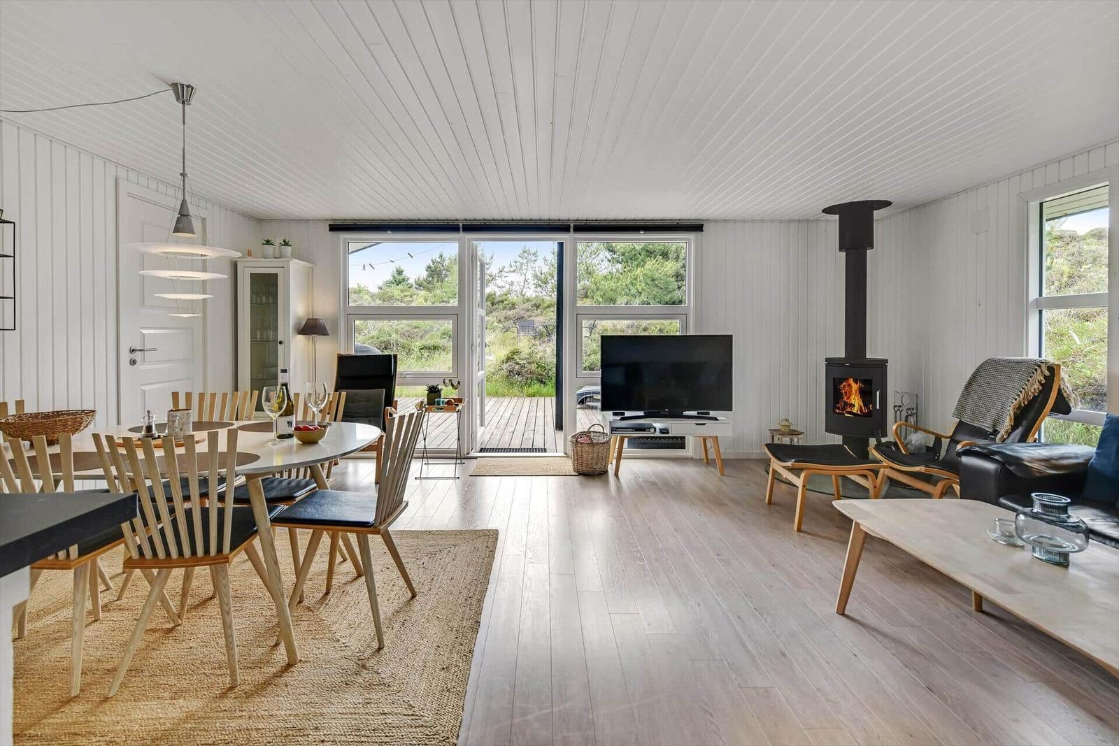 Wohn- und Essbereich mit Kamin, TV und Terrasse.