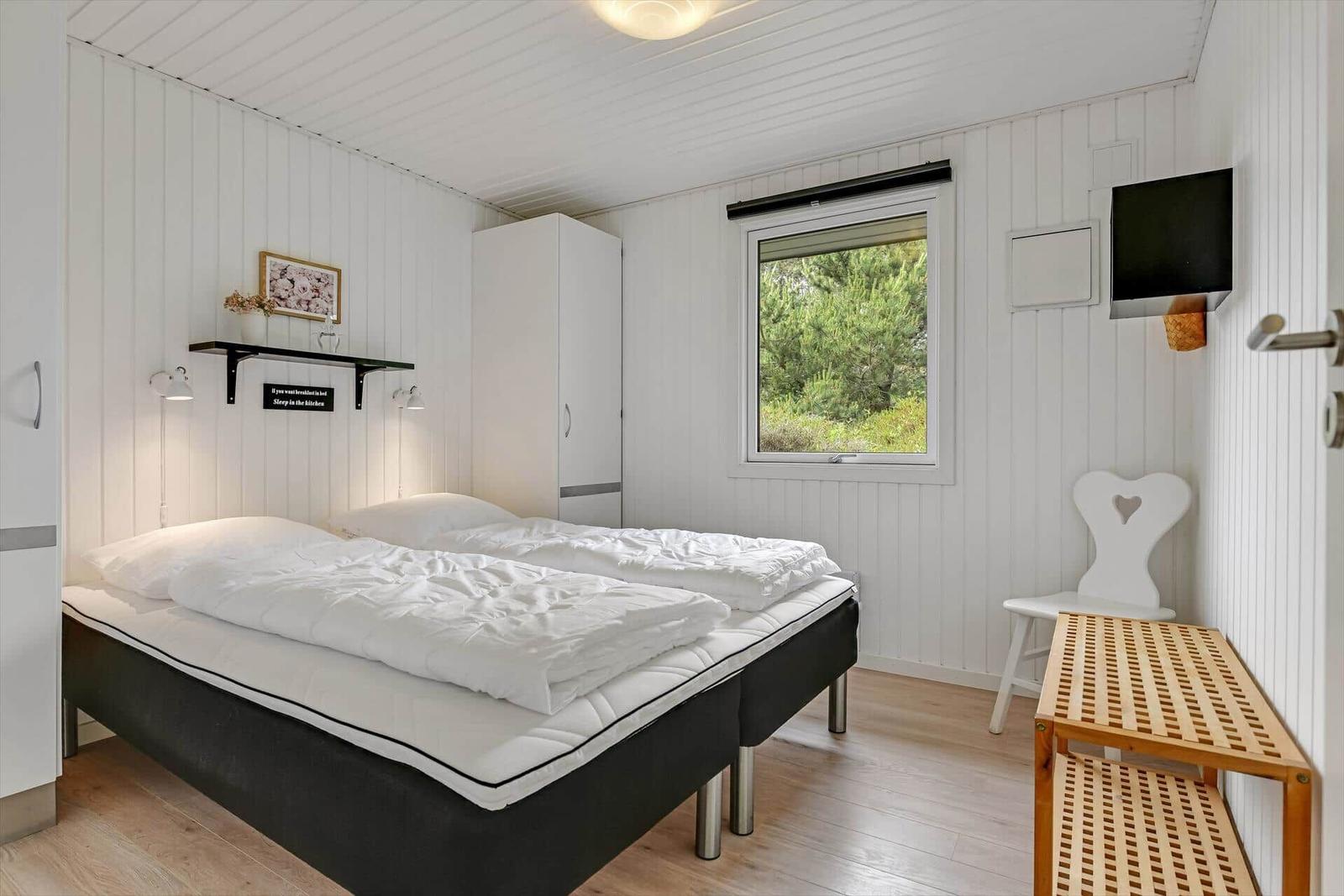 Schlafzimmer mit Doppelbett, Fenster und Kleiderschrank.