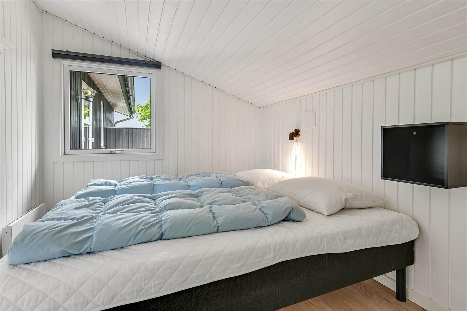 Schlafzimmer mit Bett, Fenster und Wand-TV.