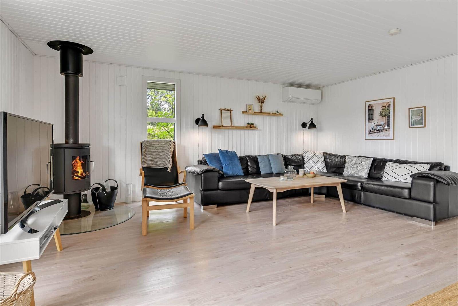 Wohnzimmer mit schwarzer Couch, Kamin und Holzboden.