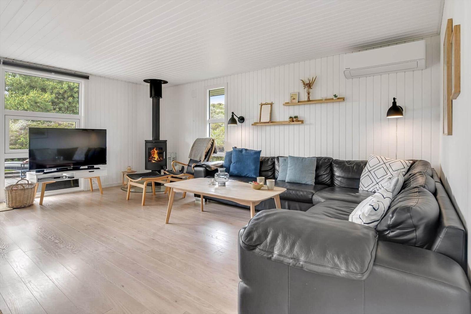 Wohnzimmer mit Sofa, Kamin und TV. Holzboden und weiße Wände.