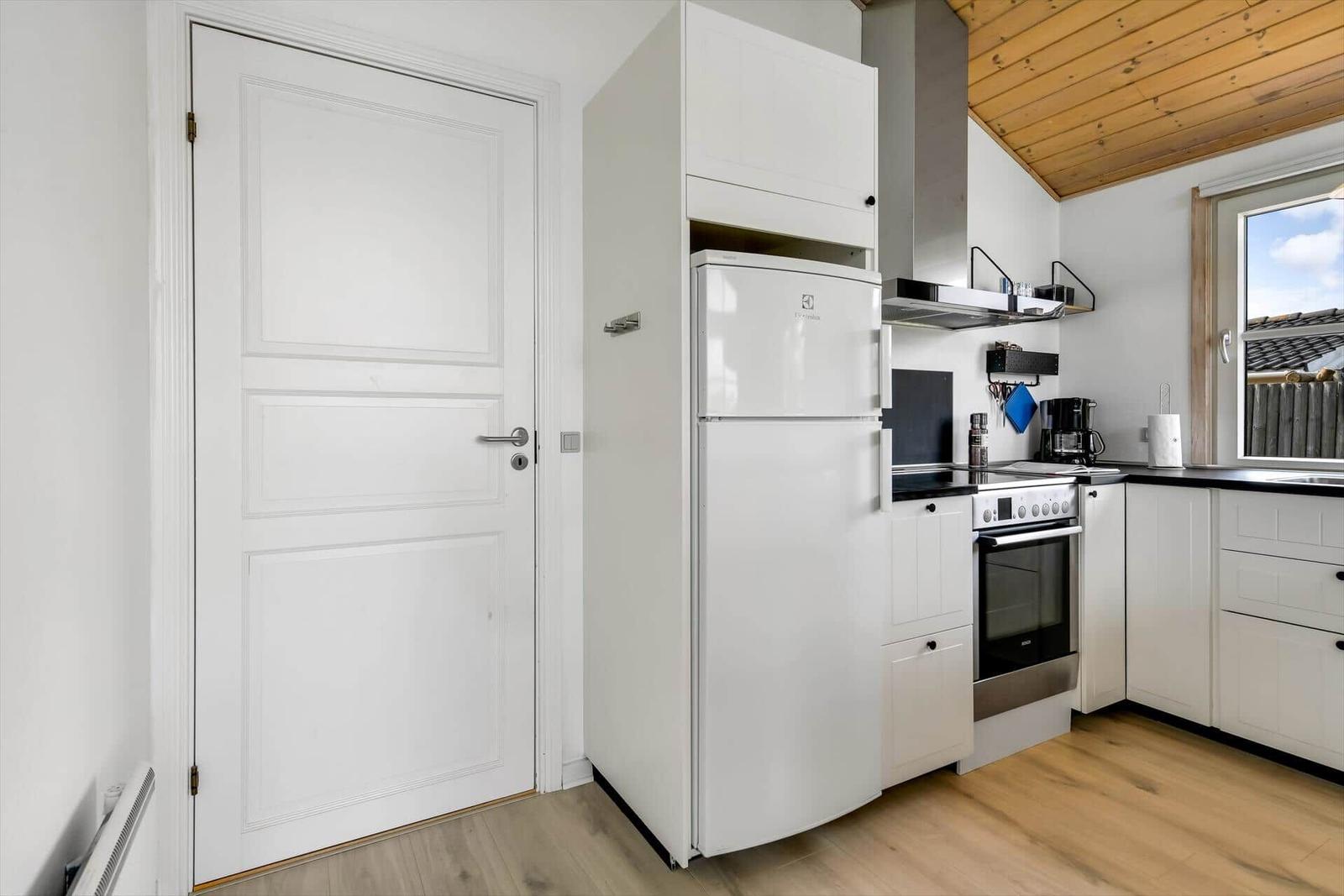 Kitchen with white refrigerator, stove, and window.