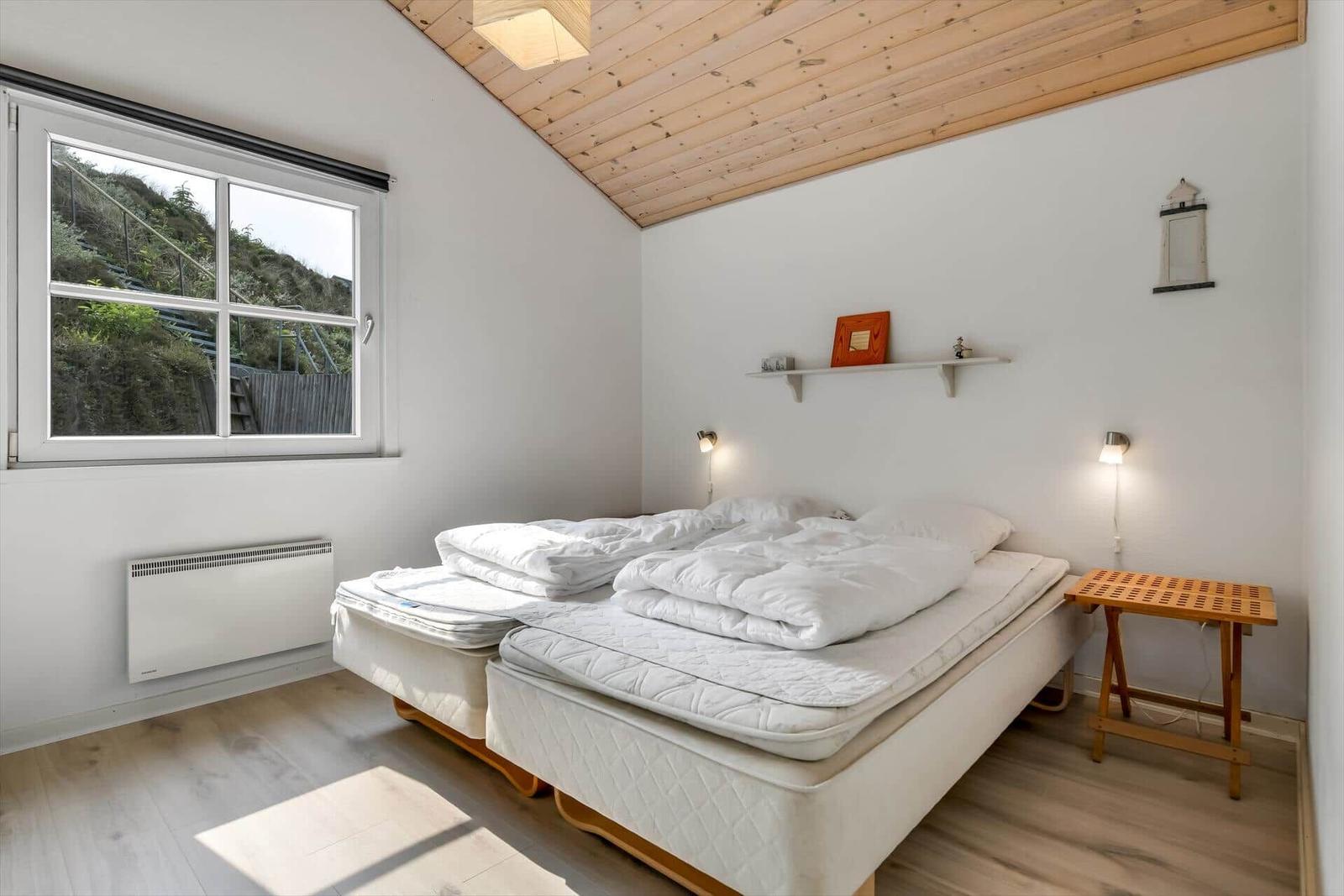 Bedroom with double bed, wooden ceiling, and window to garden.