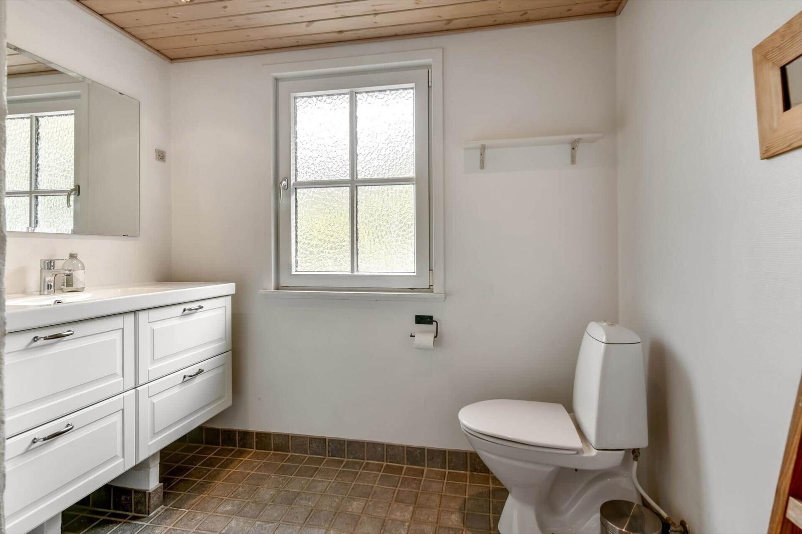 Bathroom with sink, toilet, and window with textured glass.