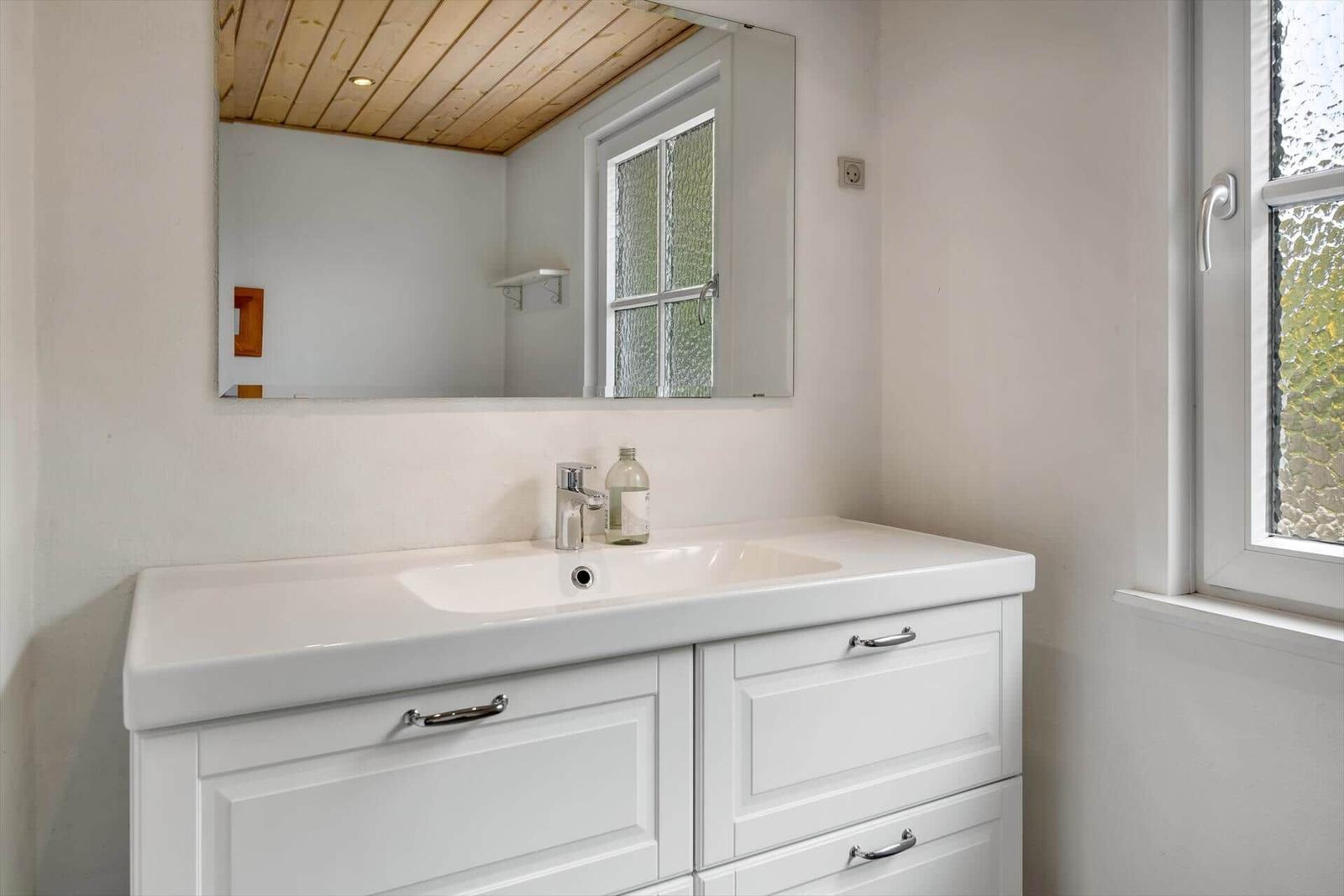Bathroom with sink, mirror, and window.
