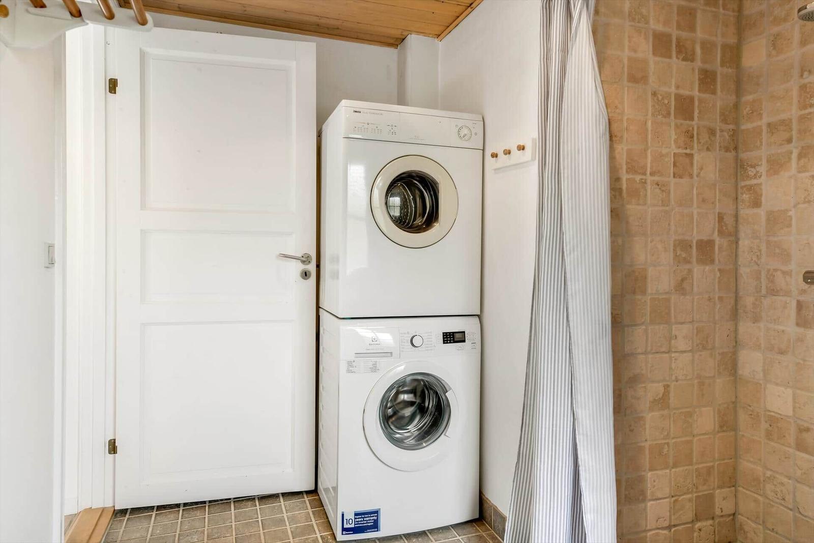 Dryer and washing machine in a room with tiled wall and door.