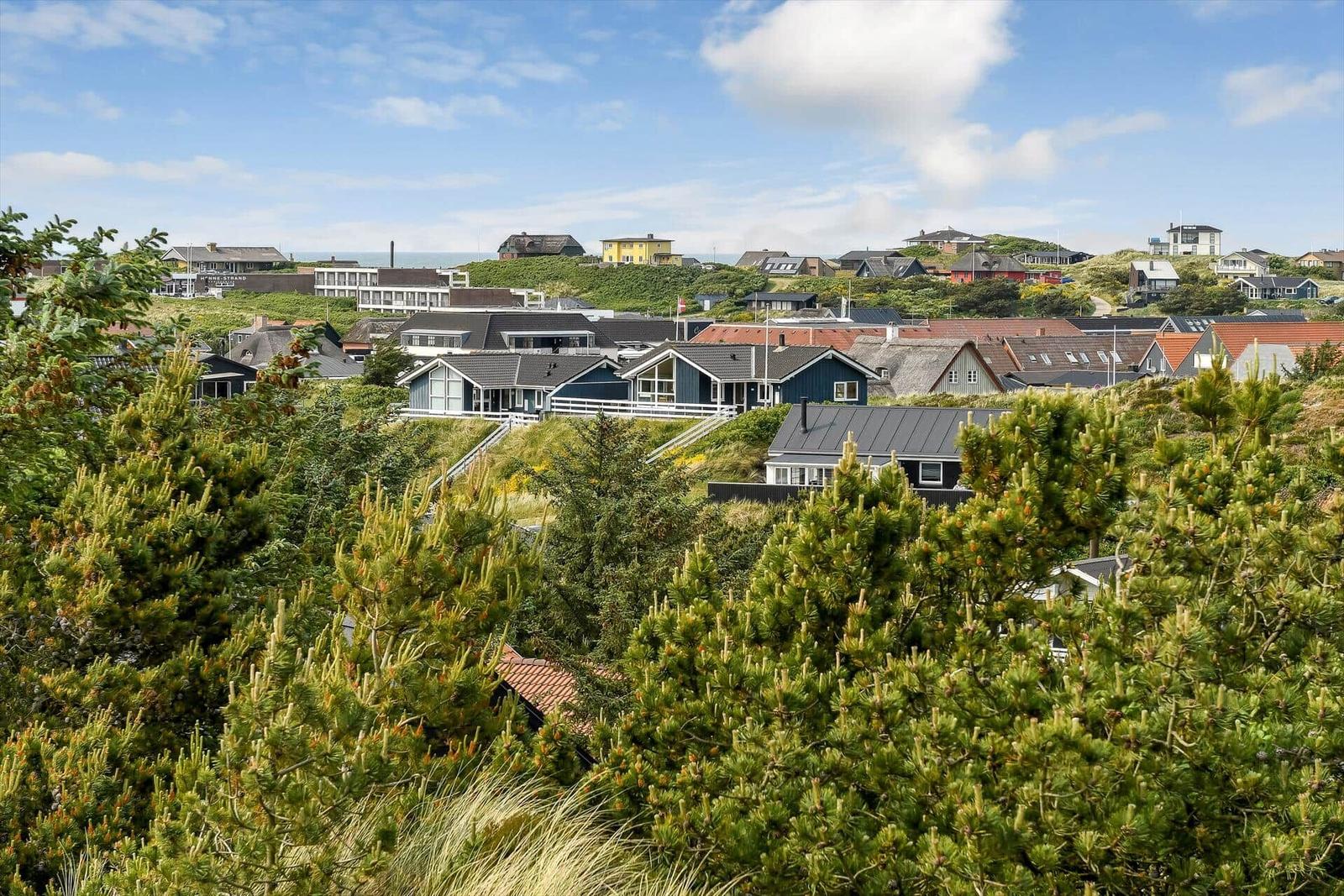 Village with houses on green hills under blue sky