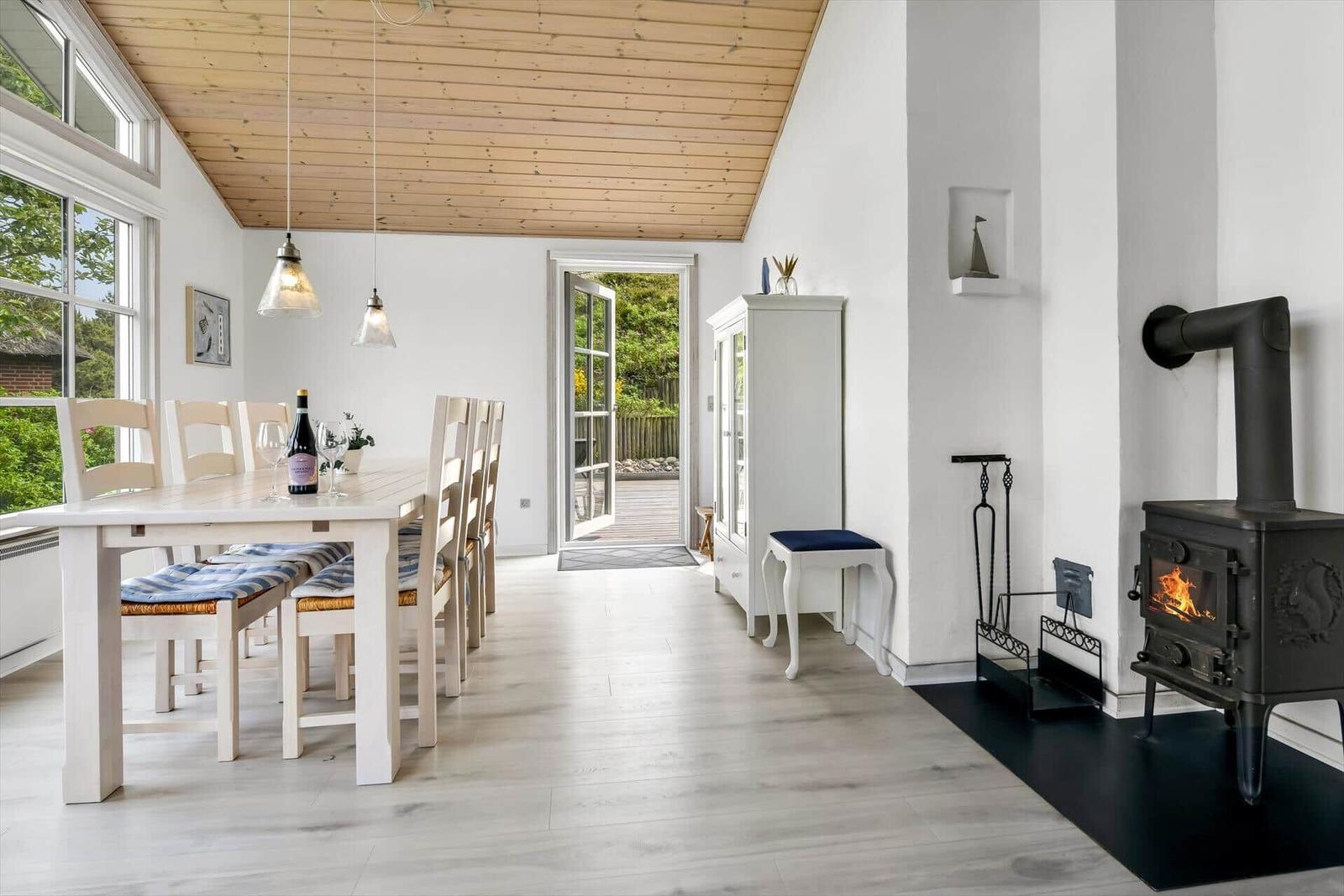 Dining room with table, chairs, and wood stove. Doorway to terrace.