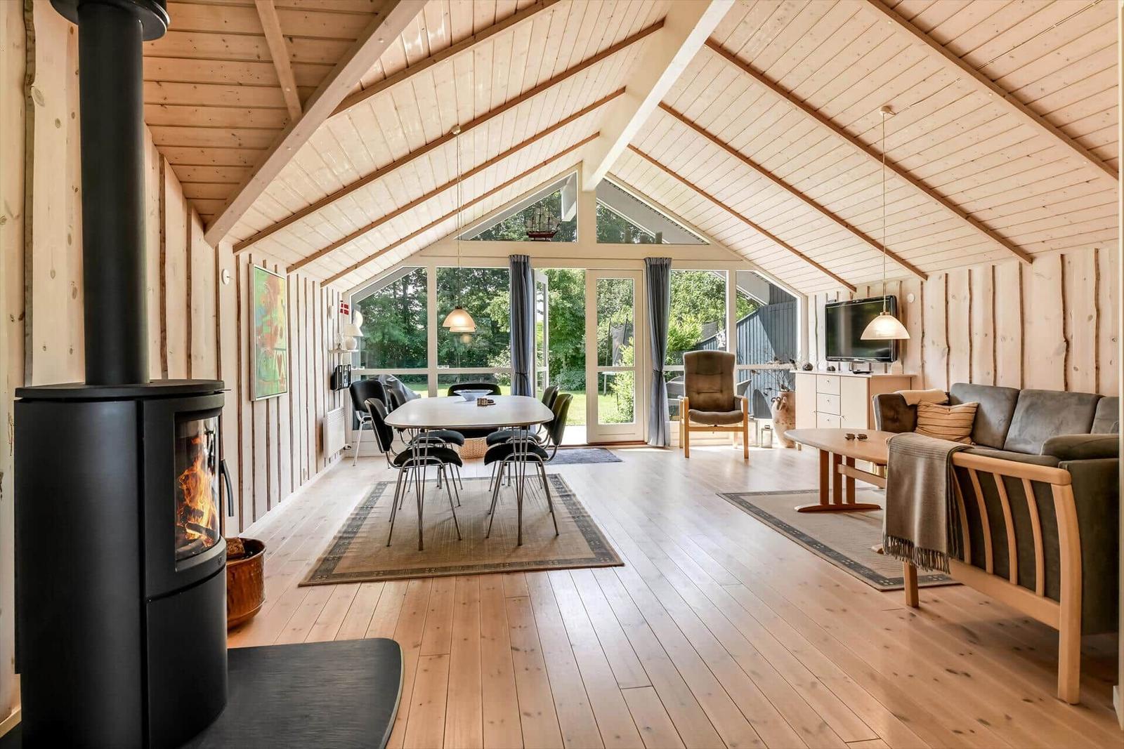 Großer Wohnbereich mit Holzdecke, Kamin und Blick auf Garten