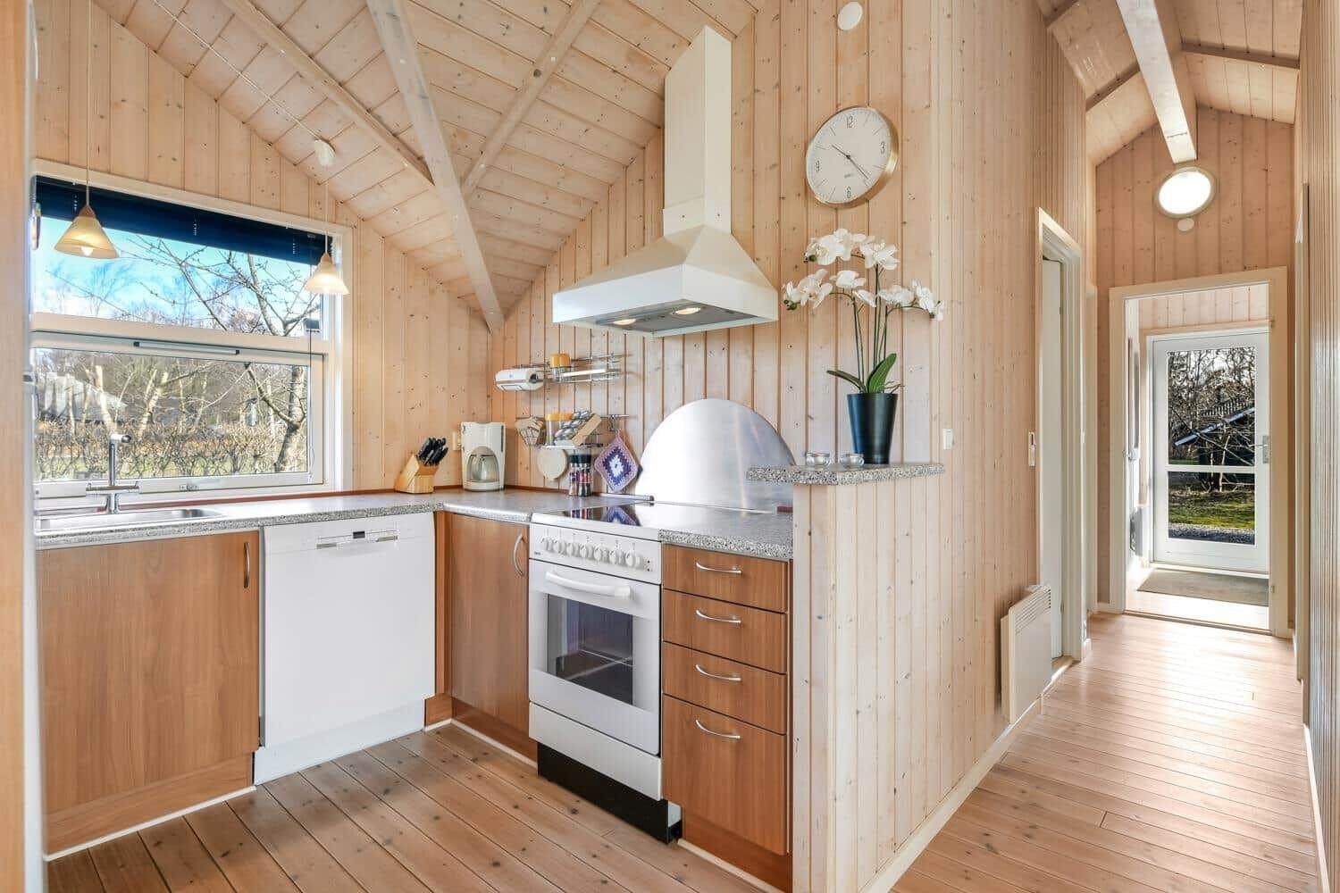 Küche mit Holzwand, Spüle, Herd und Fenster