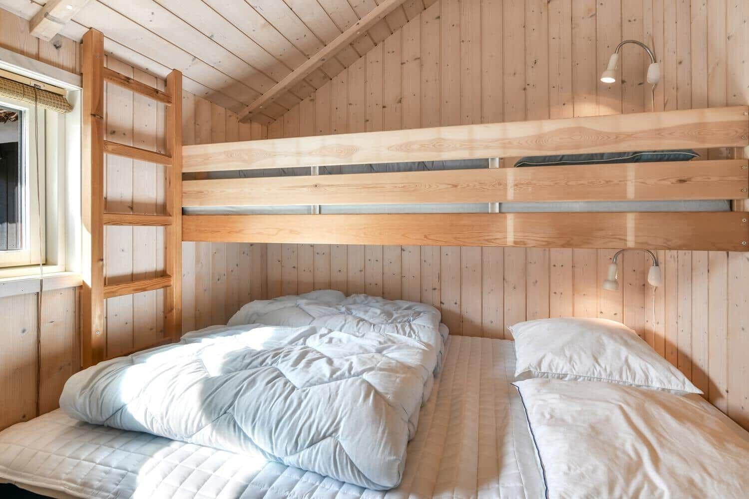 Zimmer mit Doppelbett und Obere Decke. Holzwände und Dachschrägen.