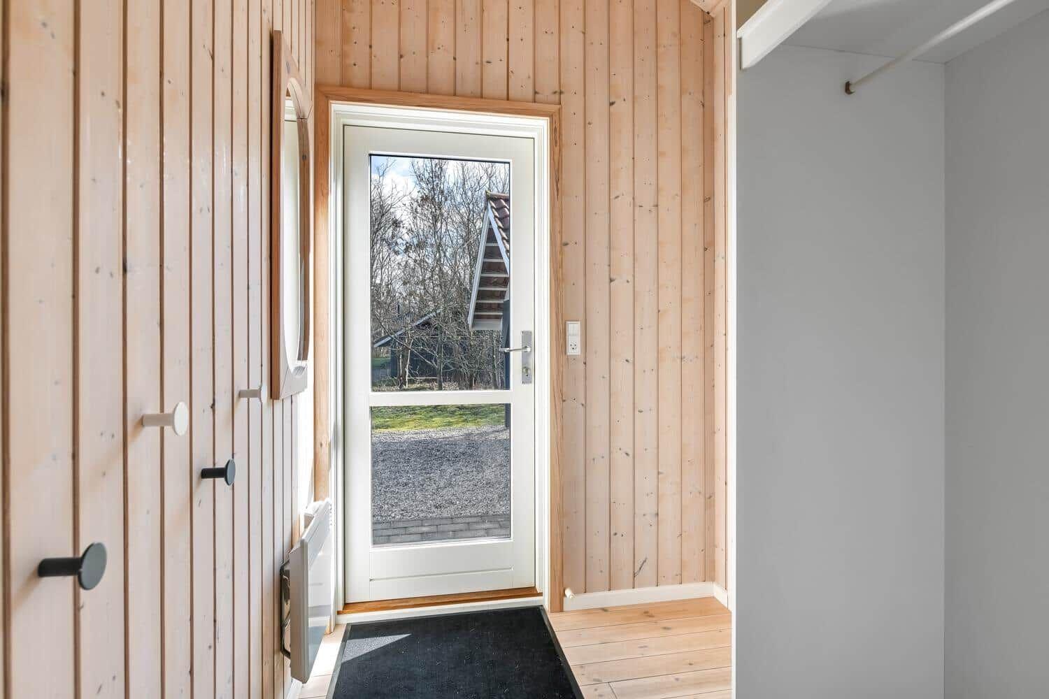 Eingangsbereich mit Holzwand und Tür zum Außenbereich