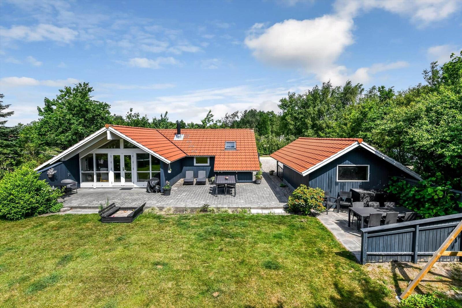 Zwei Häuser mit roten Dächern und Terrassen im Grünen.