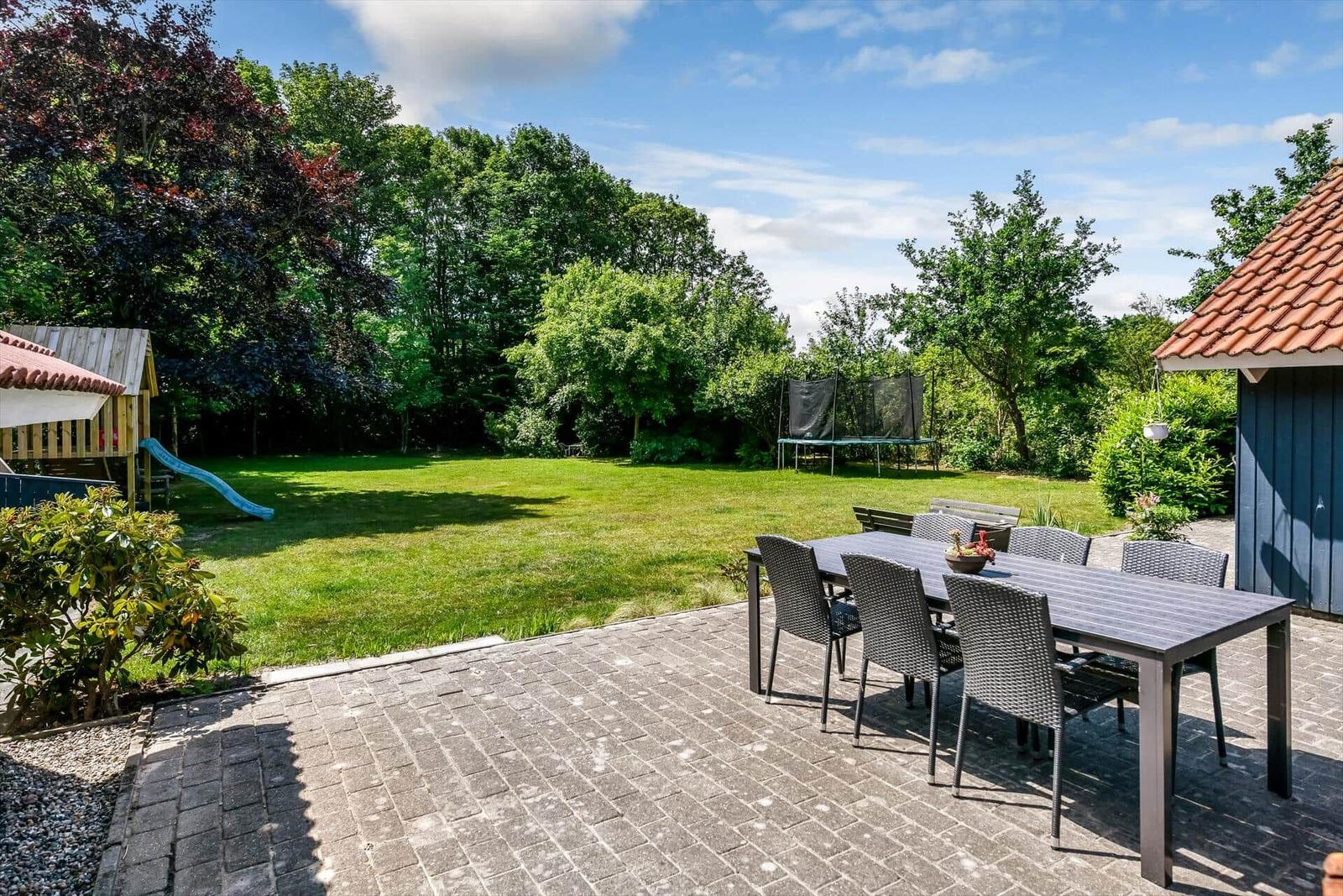 Garten mit Terrasse, Esstisch, Schaukel und Spielplatz.