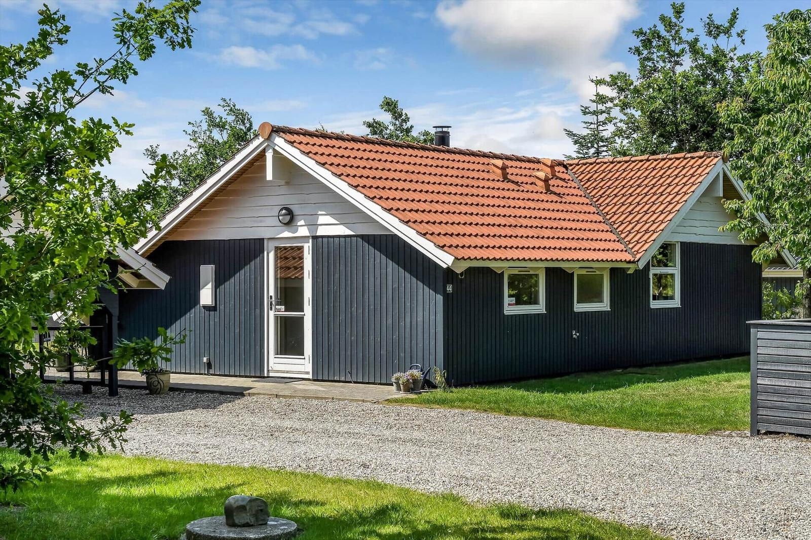 Ein dunkelblaues Ferienhaus mit rotem Dach und weißem Fensterrahmen.