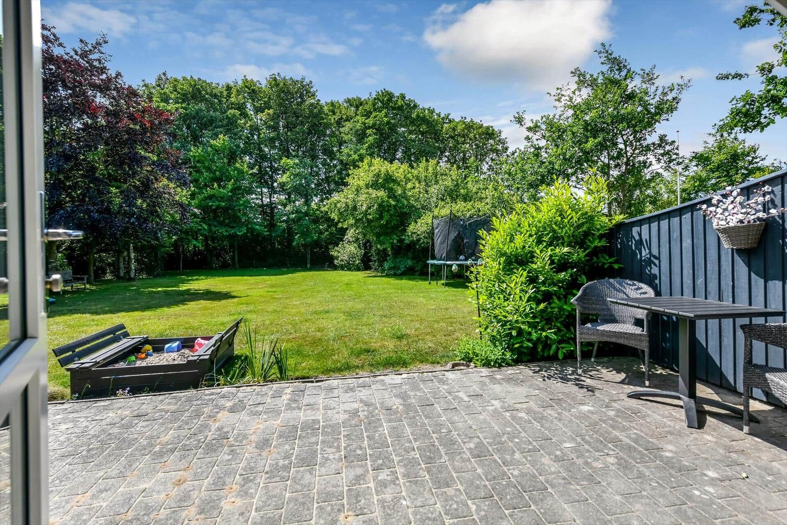 Hinterhof mit Rasen, Spielplatz und Sitzgelegenheit an der Wand.